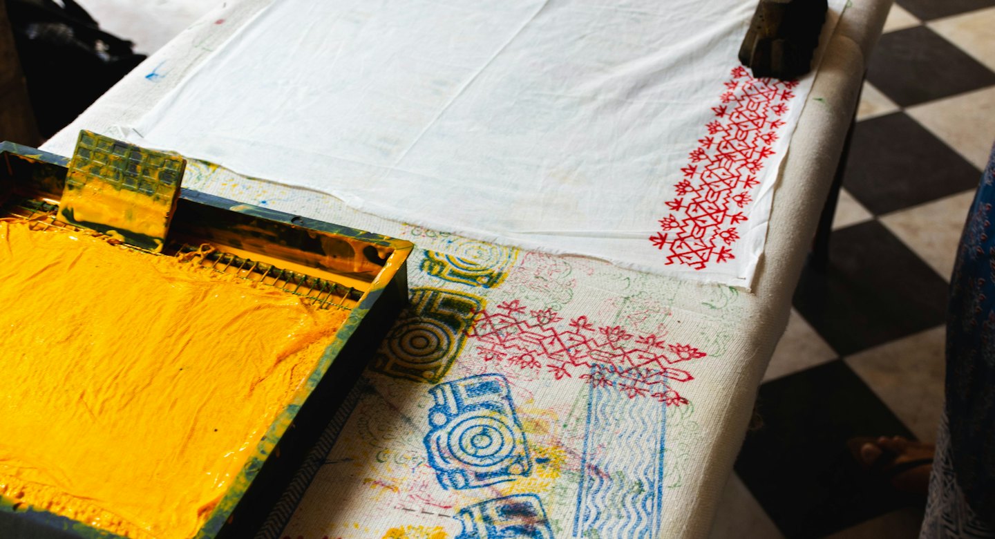 Ambachtelijk textielwerkstation met inktbak en blok bedrukte stoffen.